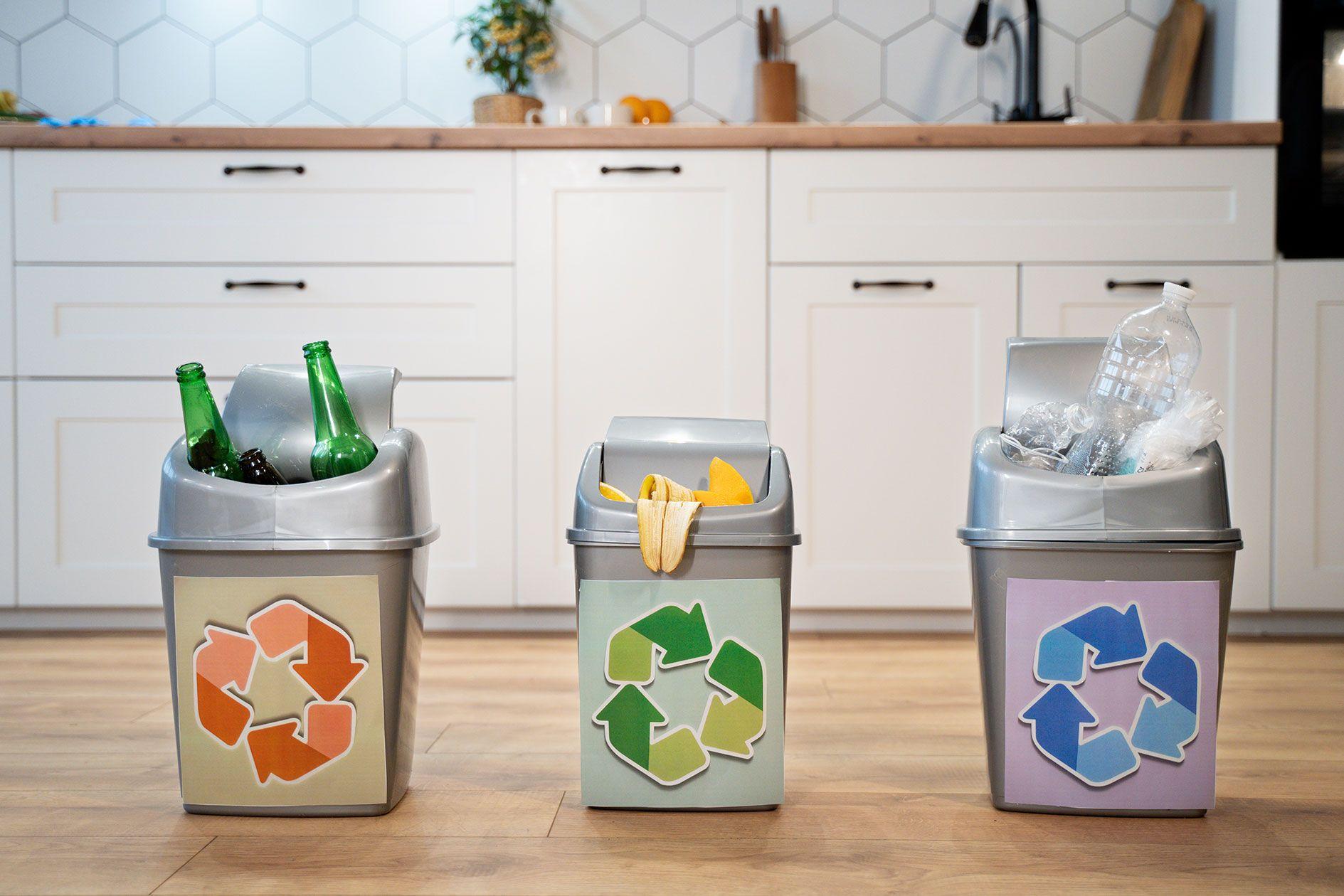 Drei separate Recyclingbehälter zur Mülltrennung in einer modernen Küche.
